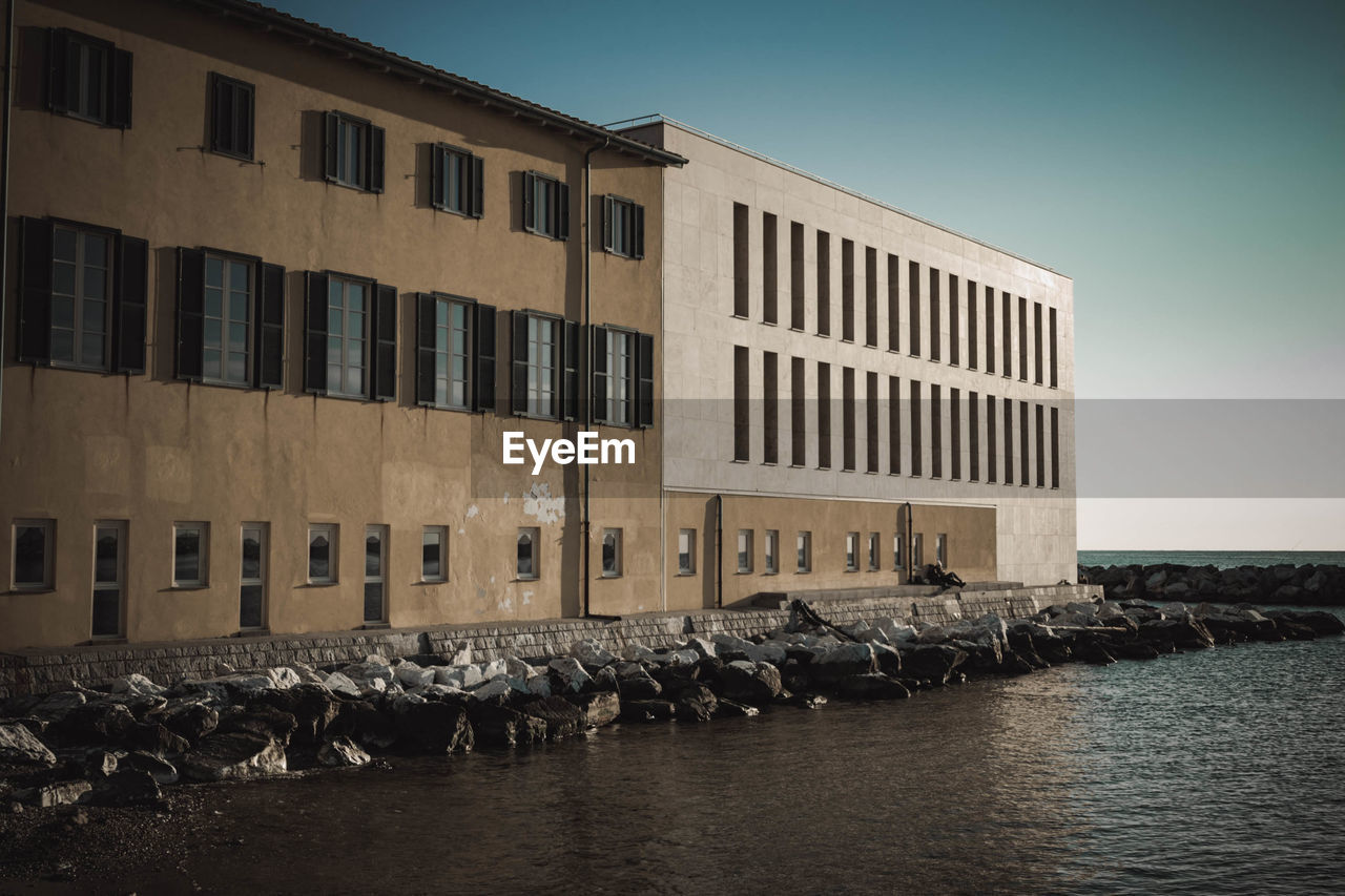 VIEW OF BUILDING BY SEA AGAINST CLEAR SKY