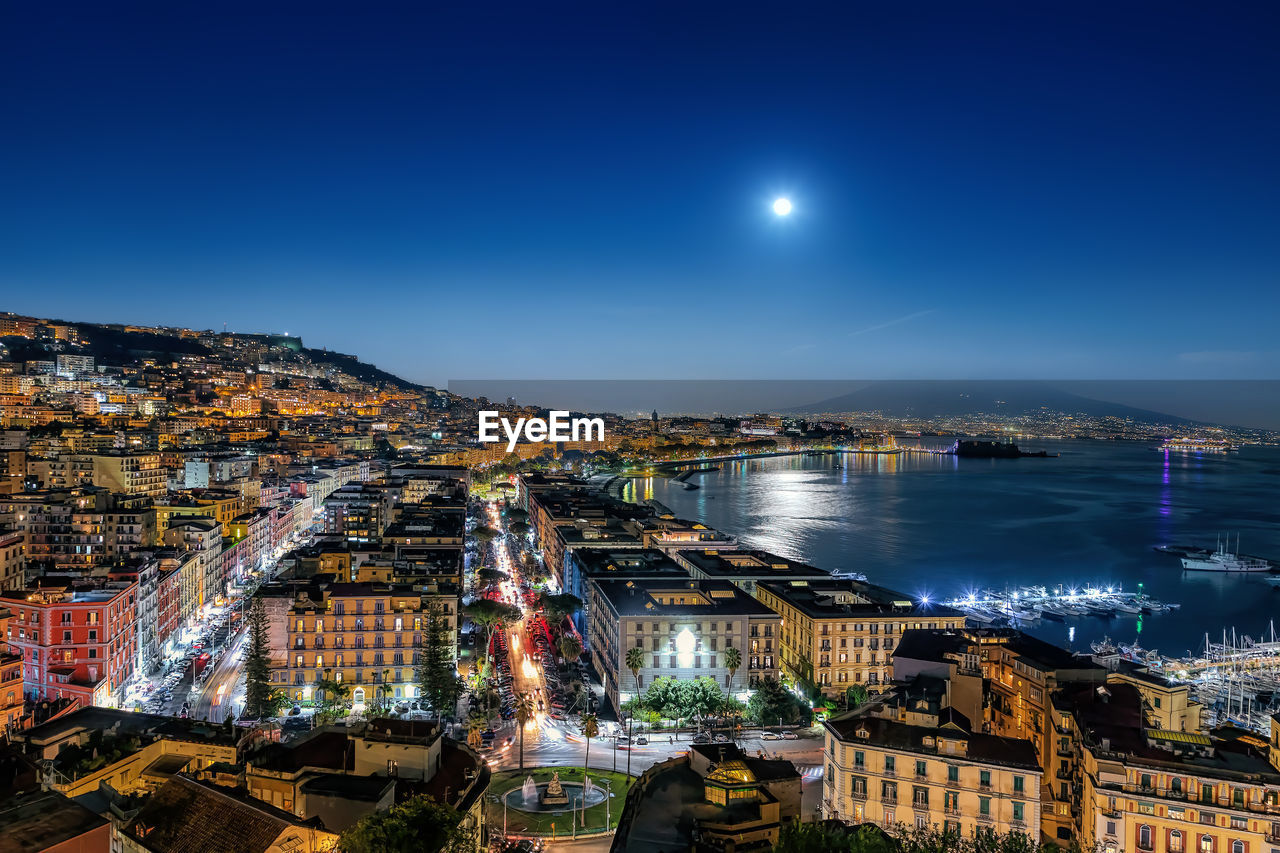 Night view of the city of naples in italy, with the waterfront and vesuvius in the background