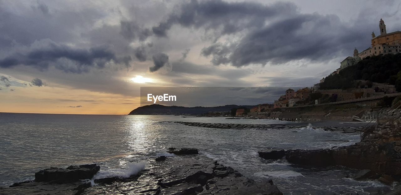 water, sky, sea, beach, cloud, land, coast, sunset, nature, shore, ocean, beauty in nature, scenics - nature, body of water, wave, travel destinations, rock, environment, travel, coastline, landscape, architecture, seascape, dramatic sky, panoramic, tourism, outdoors, dusk, evening, cliff, trip, tranquility, vacation, horizon, holiday, wind wave, bay, no people, sand, horizon over water, sun, terrain, building, motion, storm, tranquil scene, built structure, reflection, building exterior