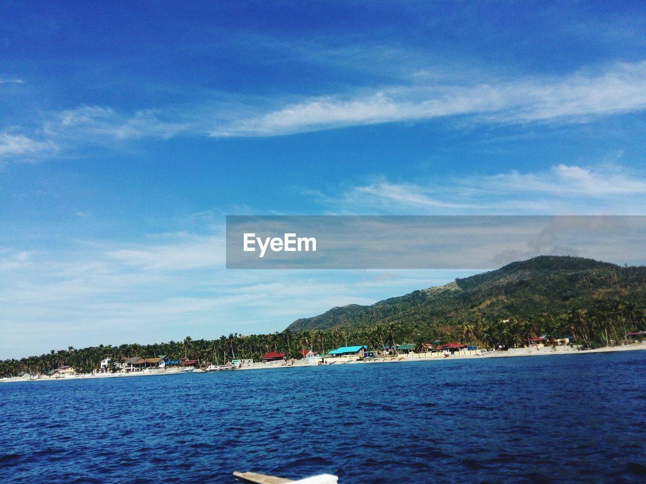 SCENIC VIEW OF SEA BY MOUNTAINS AGAINST BLUE SKY