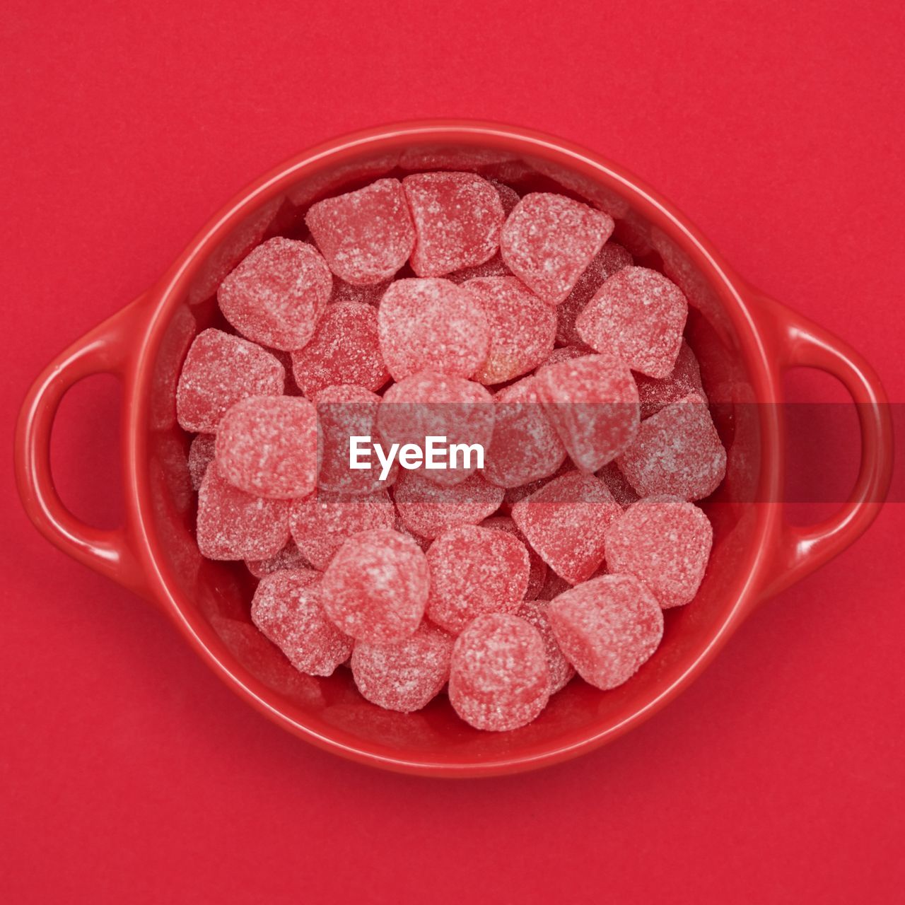 Directly above view of candies in bowl on red background