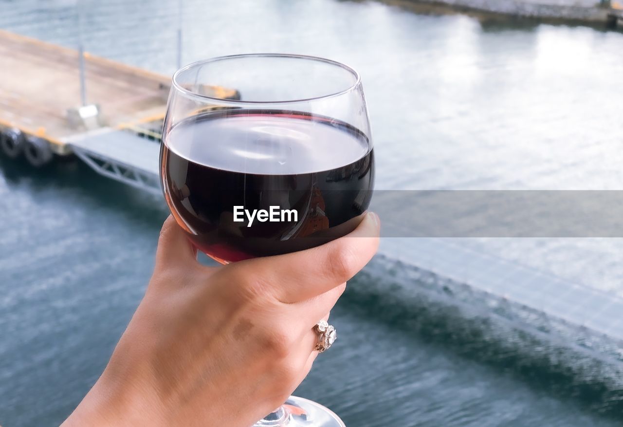 Glass of red wine in womans hand during cruise vacation.