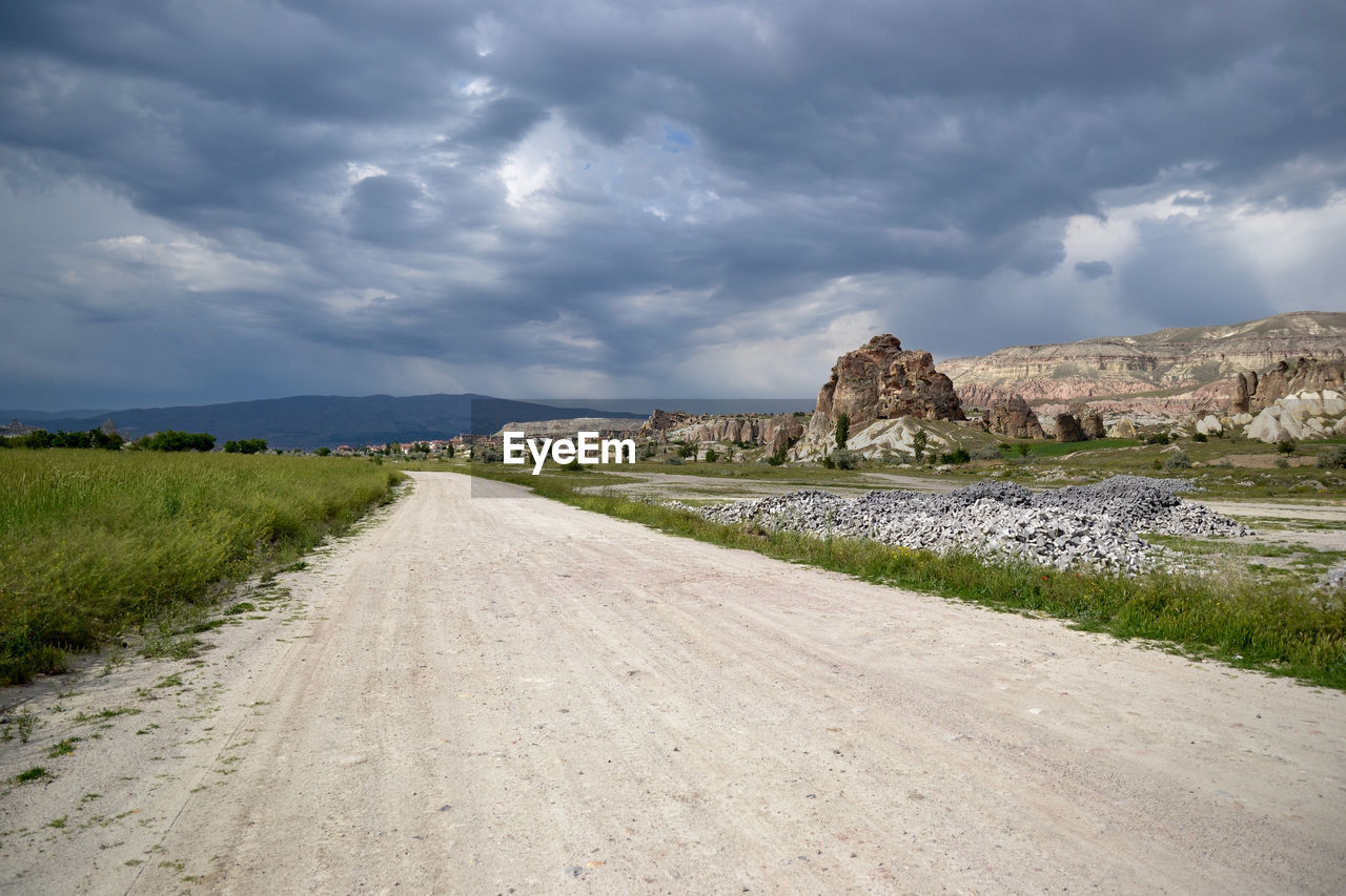 Road passing through landscape against cloudy sky