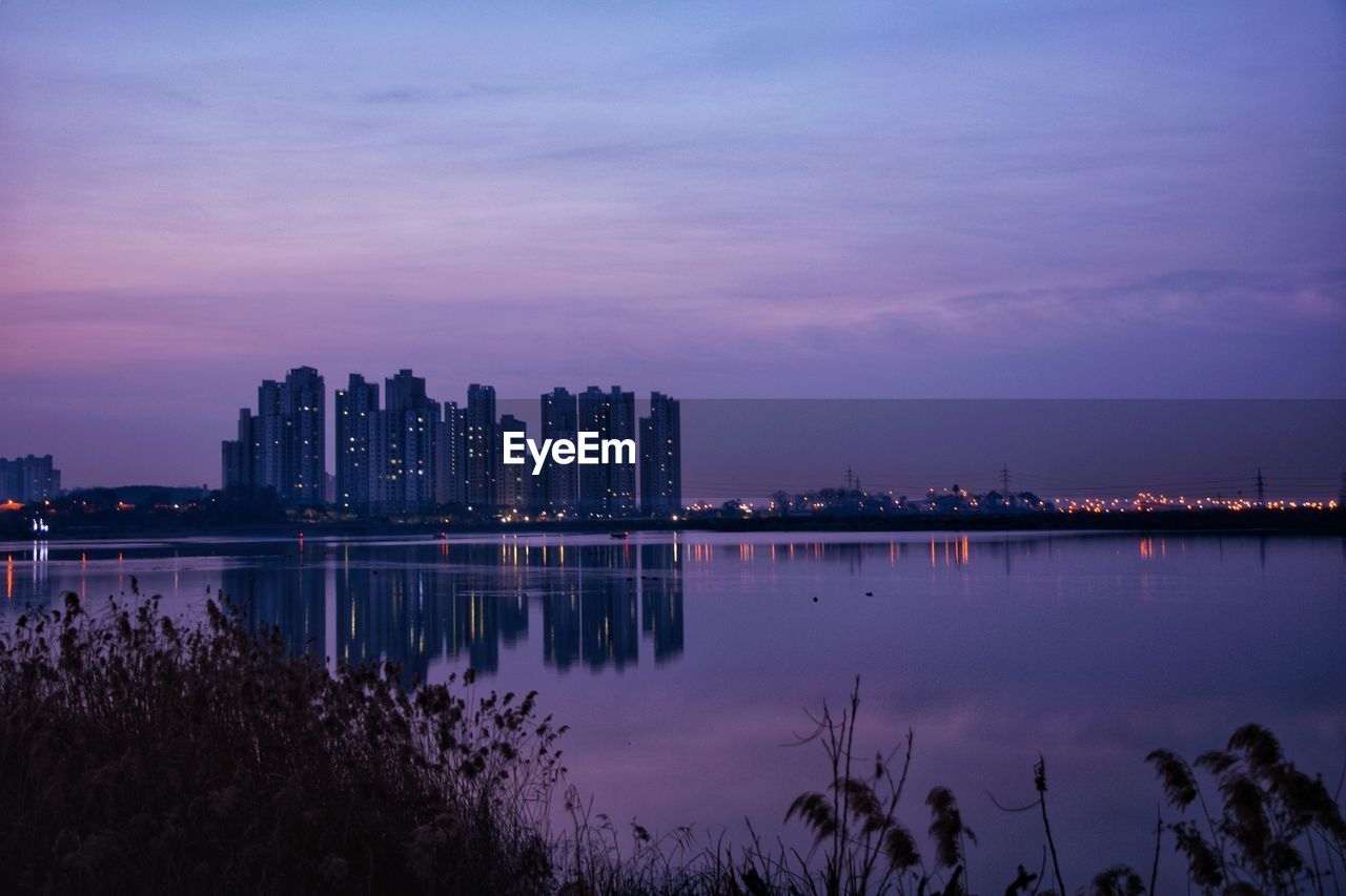 Reflection of buildings in lake at dawn