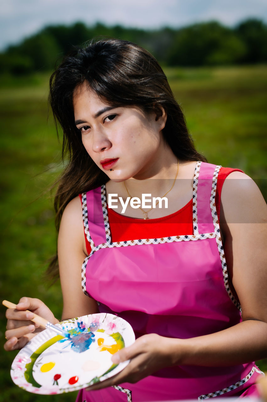 Portrait of young woman holding brush and colour pallet. 