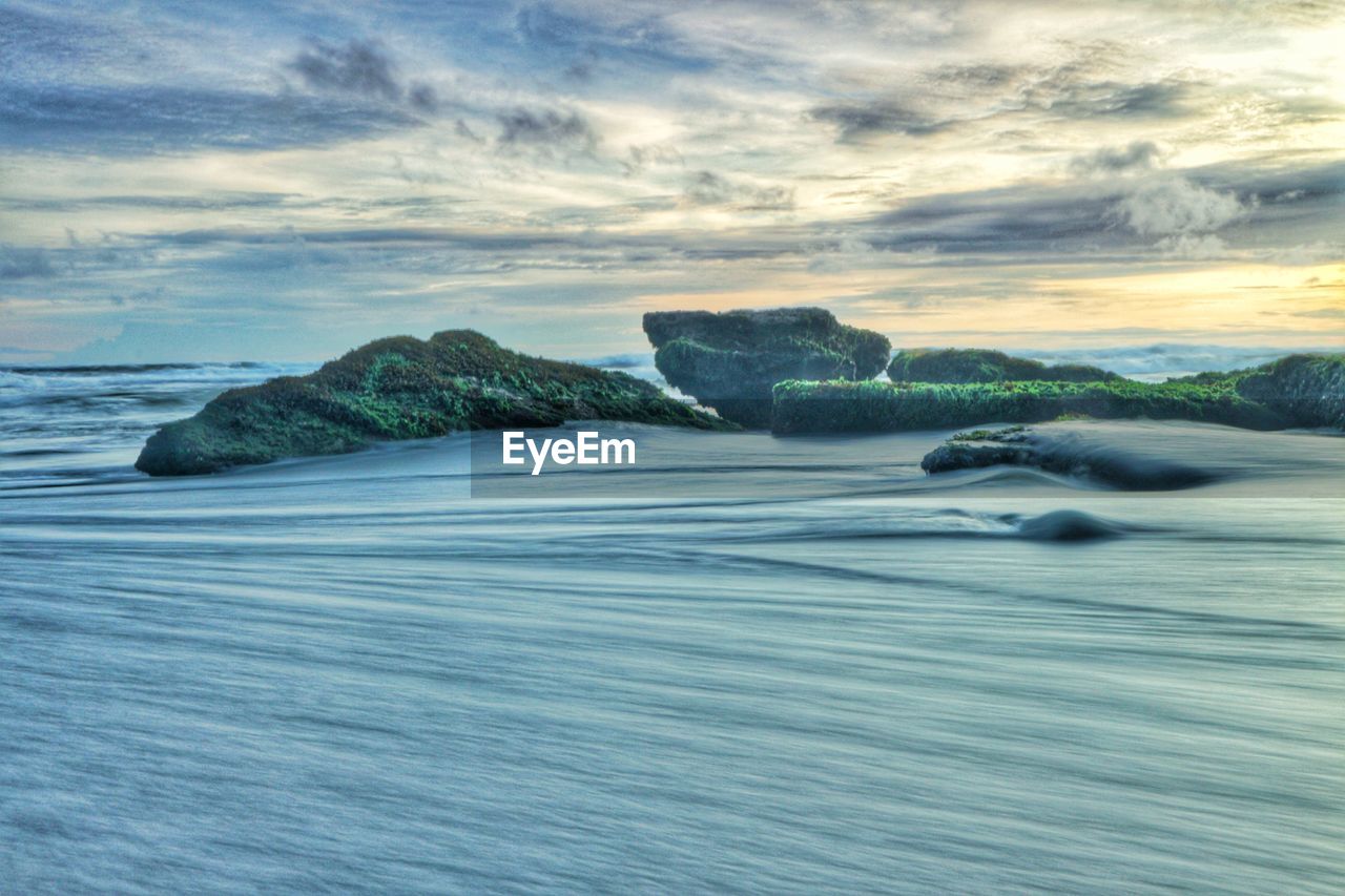 Surface level of rocks on shore against sky