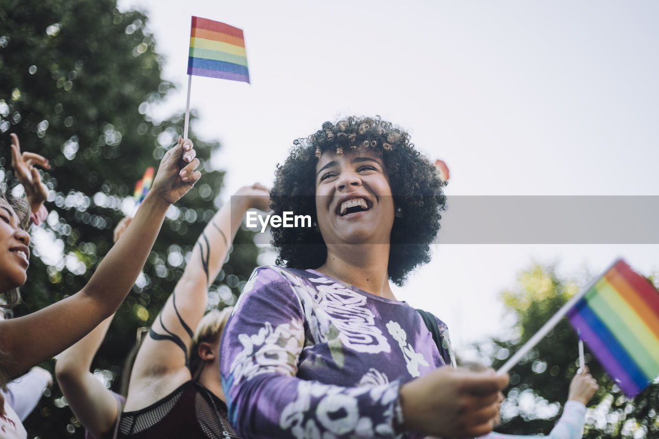 Happy transgender woman with rainbow flag enjoying in gay pride parade