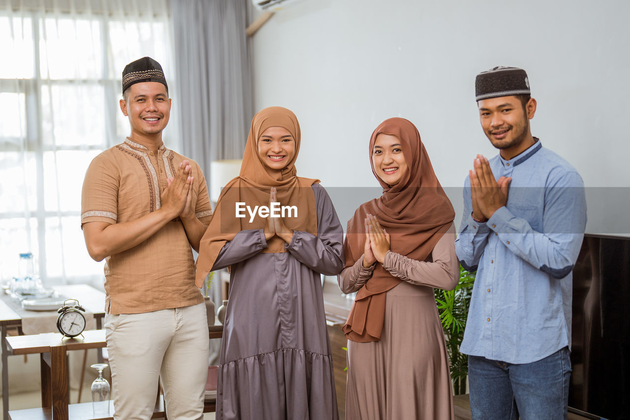 Portrait of smiling family with hands clasped at home