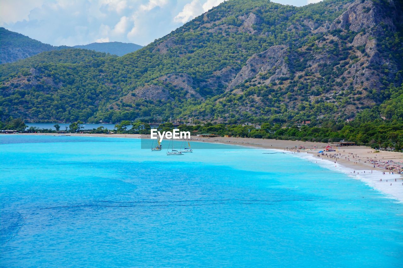 SCENIC VIEW OF SWIMMING POOL BY SEA AGAINST MOUNTAIN