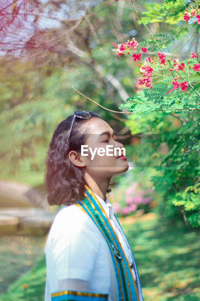 Side view of woman standing by branches at park