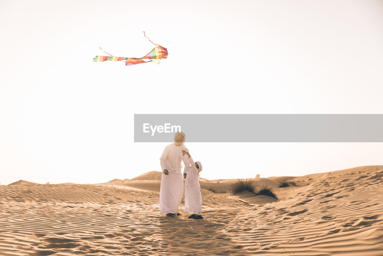 Full length of father with son flying kite in desert