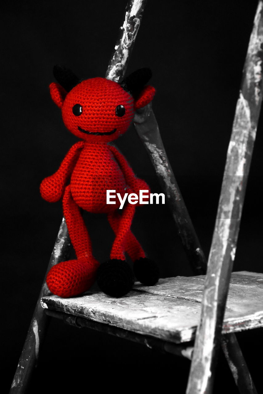 red, no people, toy, black background, studio shot, representation, indoors, hanging, close-up, human representation, cartoon, wood, craft