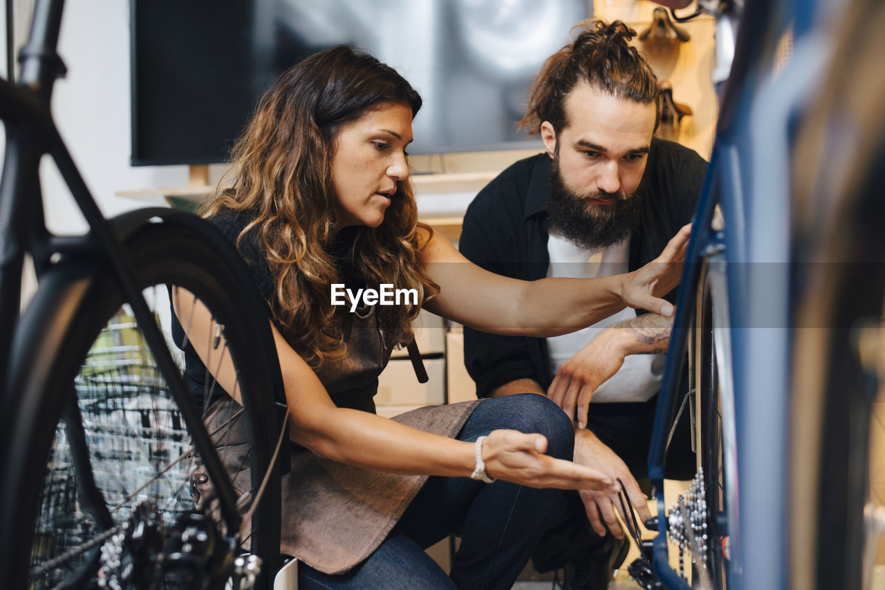 Female entrepreneur selling bicycle to male customer in repair shop