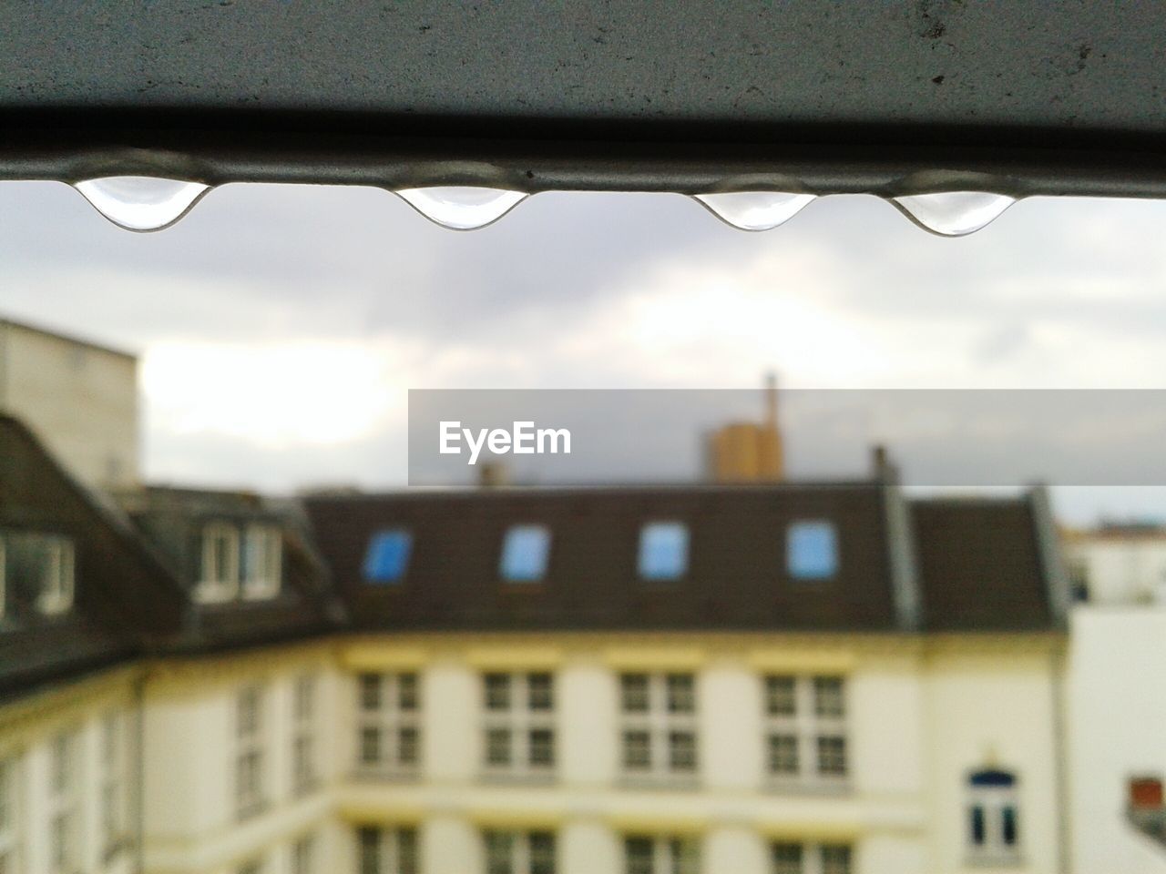 Close-up of rain drops on metal against residential building