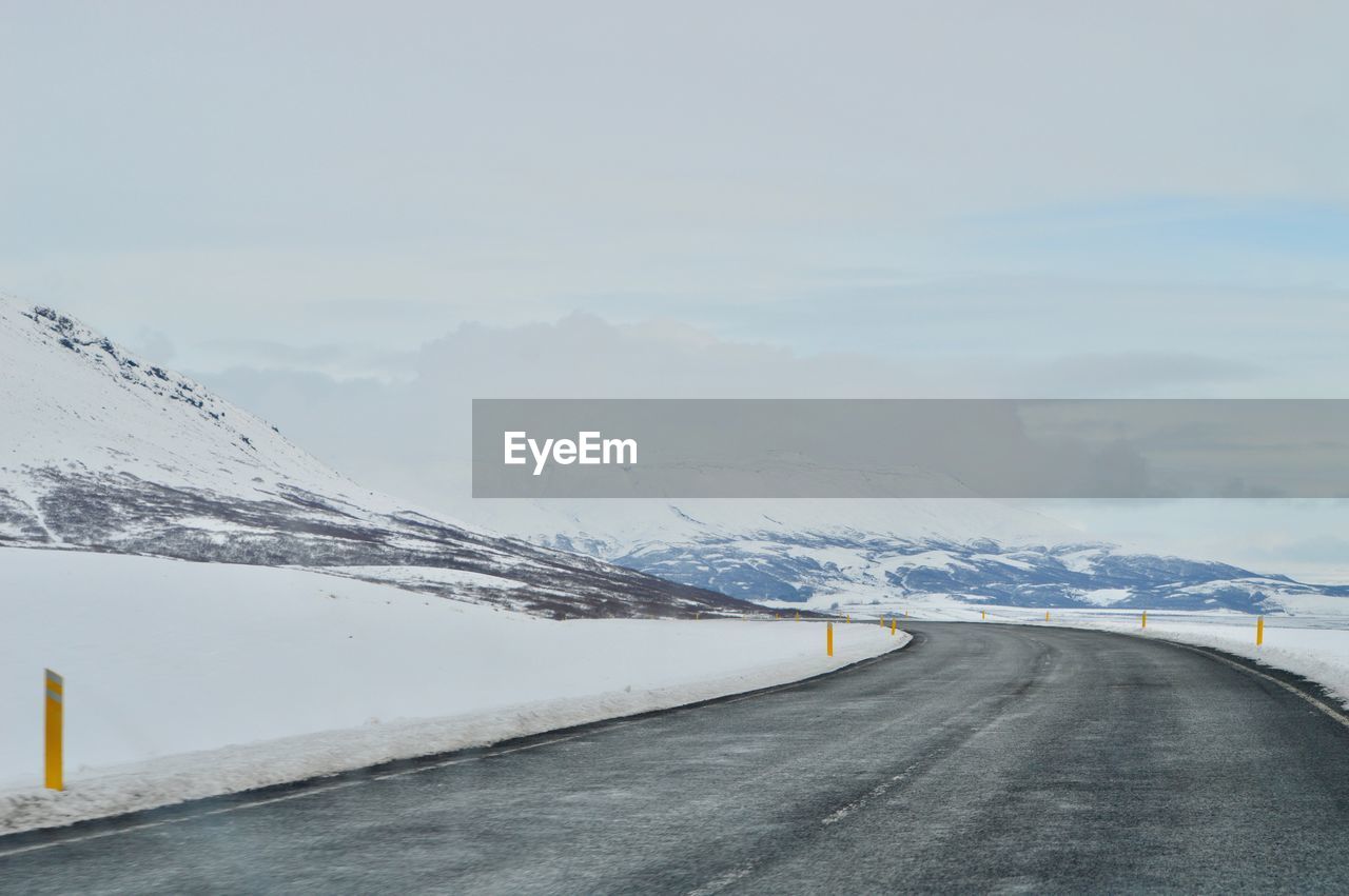 Road amidst snowcapped mountains against sky