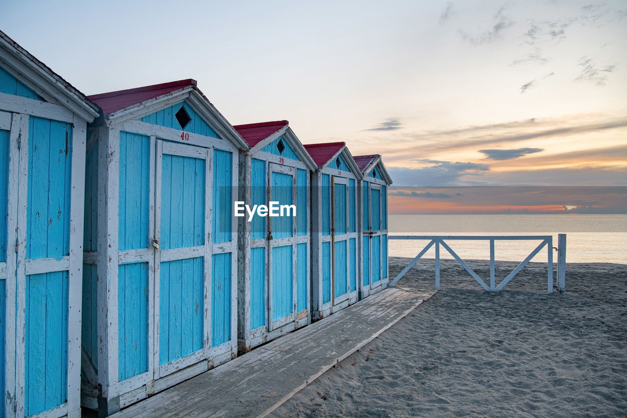 Beach hut against sky during sunset. old blue houses on the sea shore 