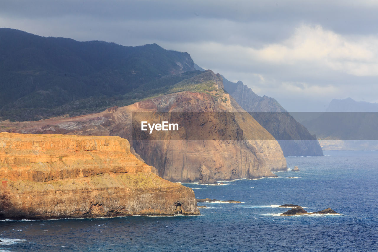 Scenic view of sea and mountains against sky