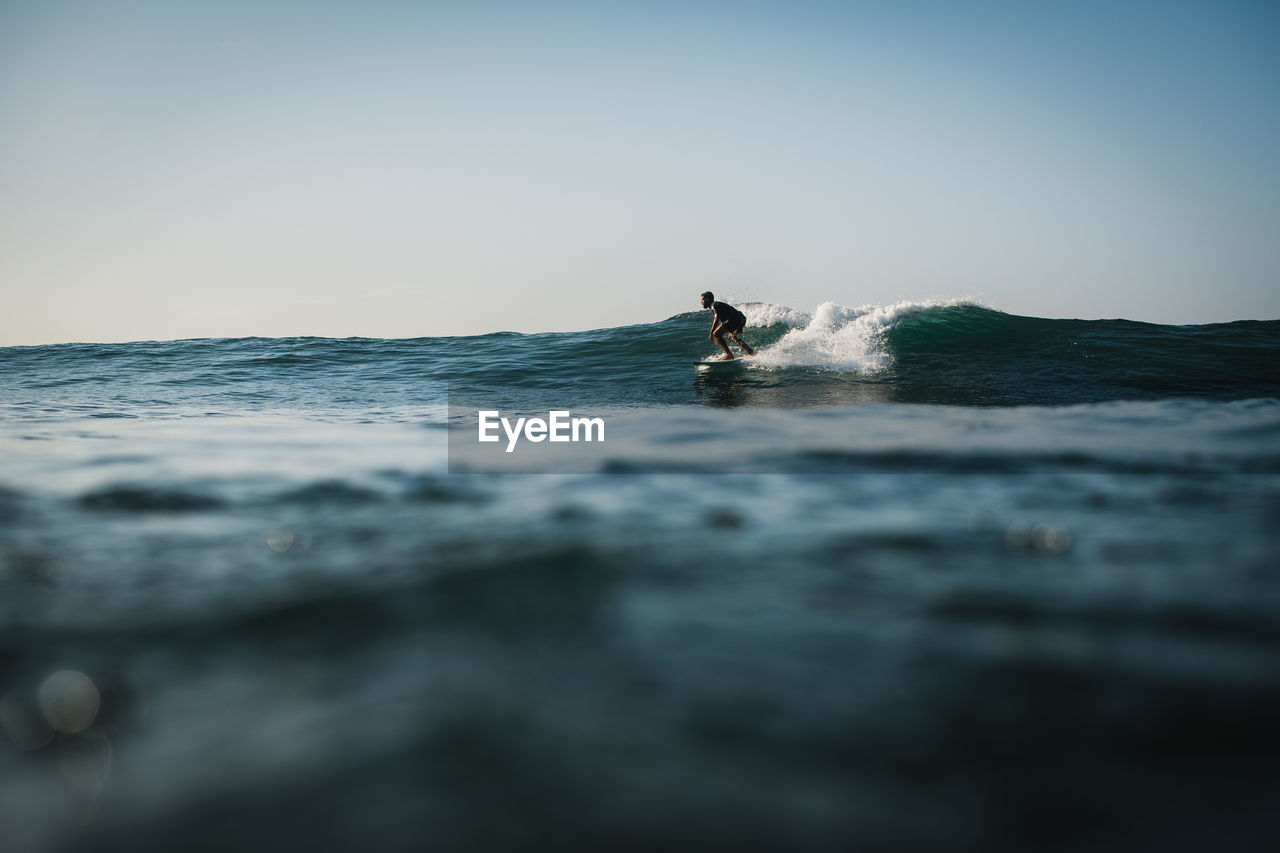 Man surfing on sea against clear sky