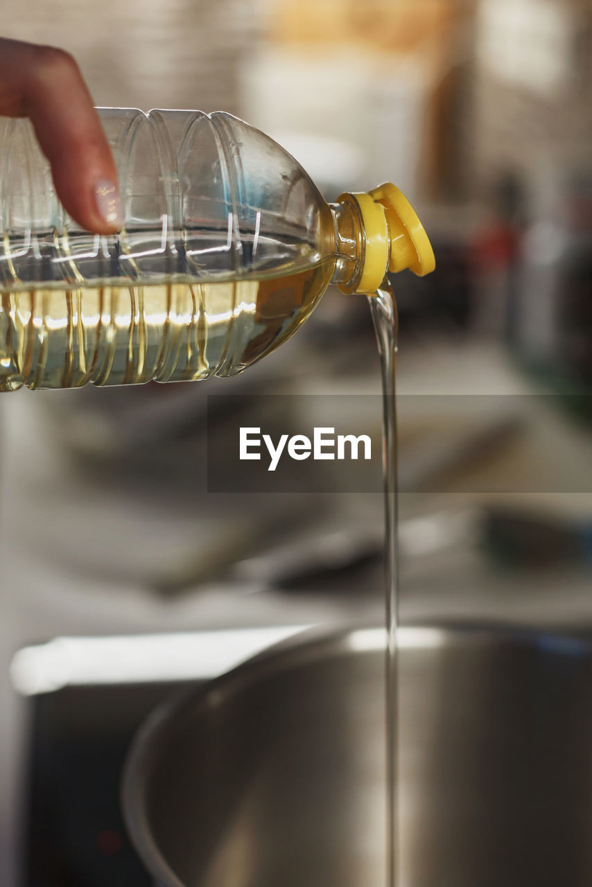 Close up of pouring vegetable oil into deep cooking stainless steel pot