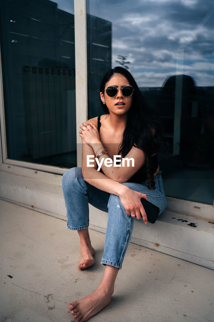 Young woman wearing sunglasses sitting outdoors