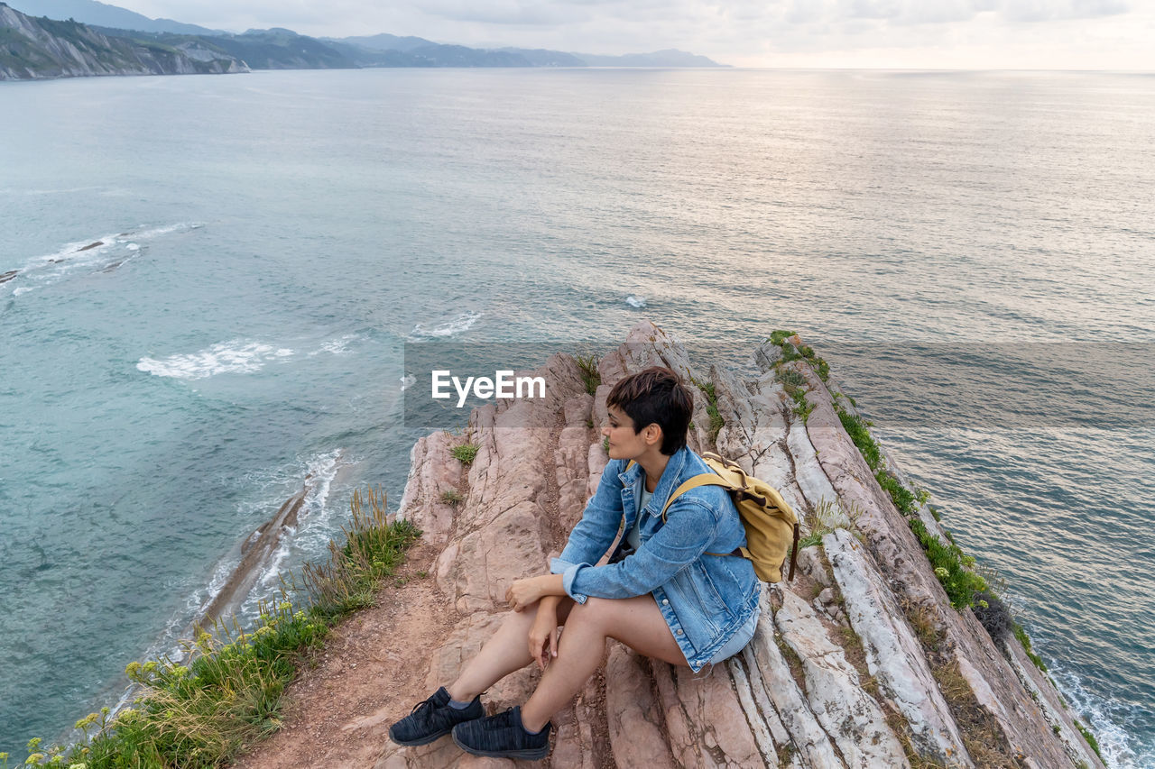 side view of woman sitting on pier