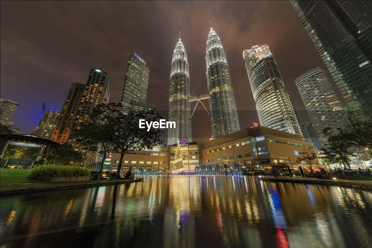 LOW ANGLE VIEW OF ILLUMINATED SKYSCRAPERS AGAINST SKY AT NIGHT