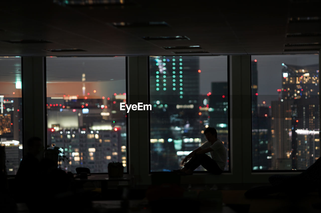 PEOPLE SITTING AT ILLUMINATED BUILDING AT NIGHT