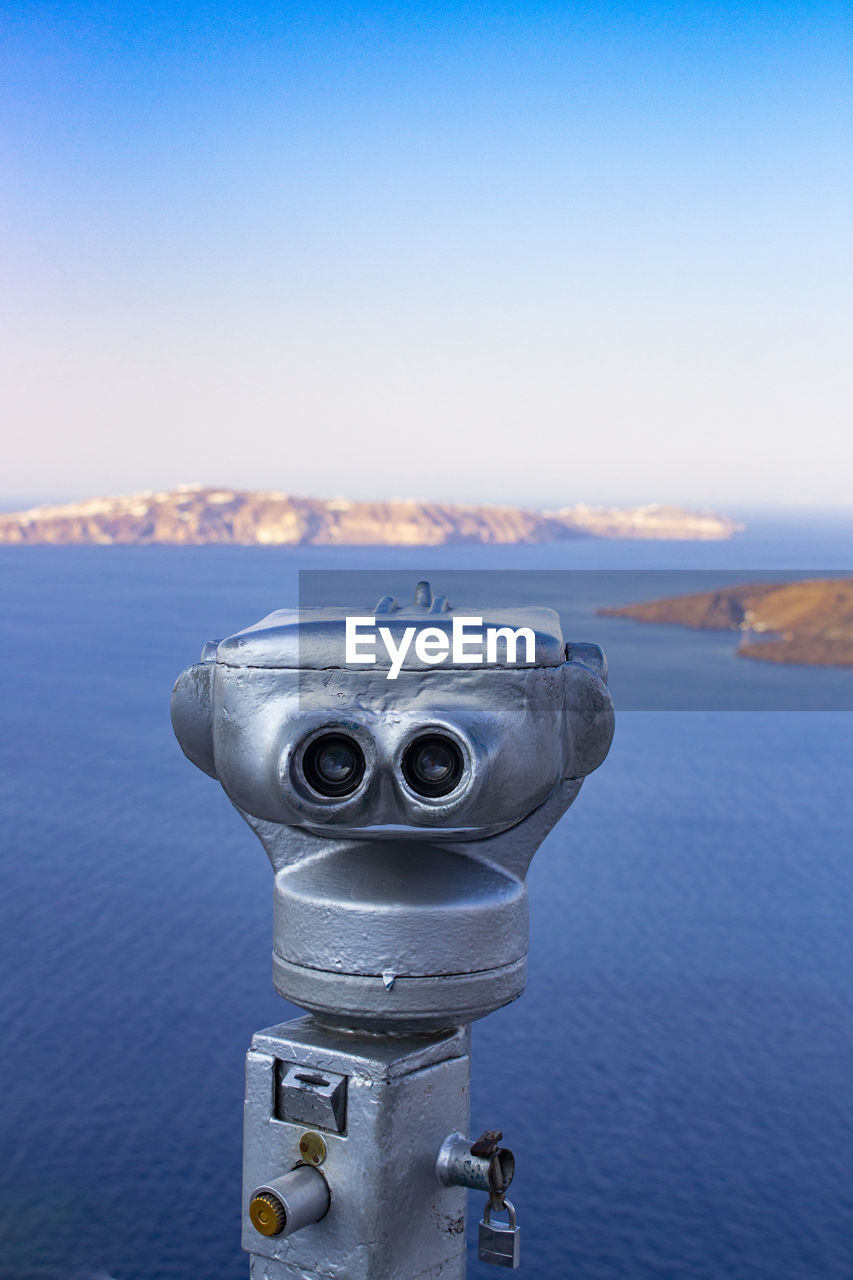 Close-up of coin-operated binoculars by sea against sky