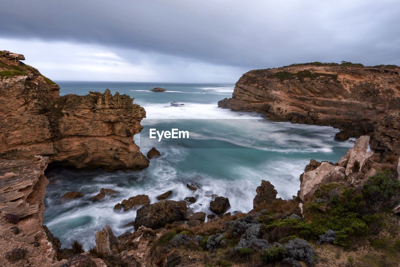 Rock formation on sea shore against sky