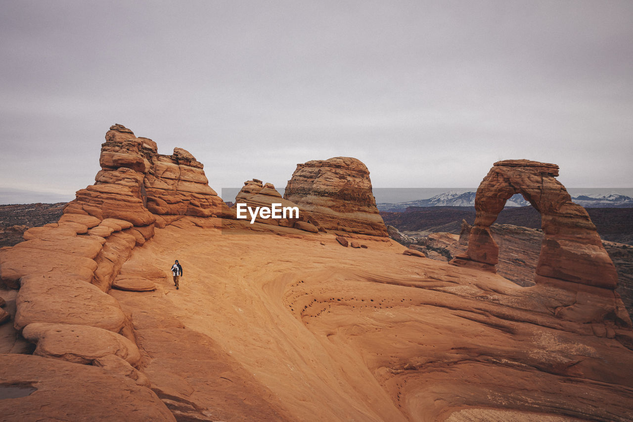 A man with a child is standing near delicate arch at arches np