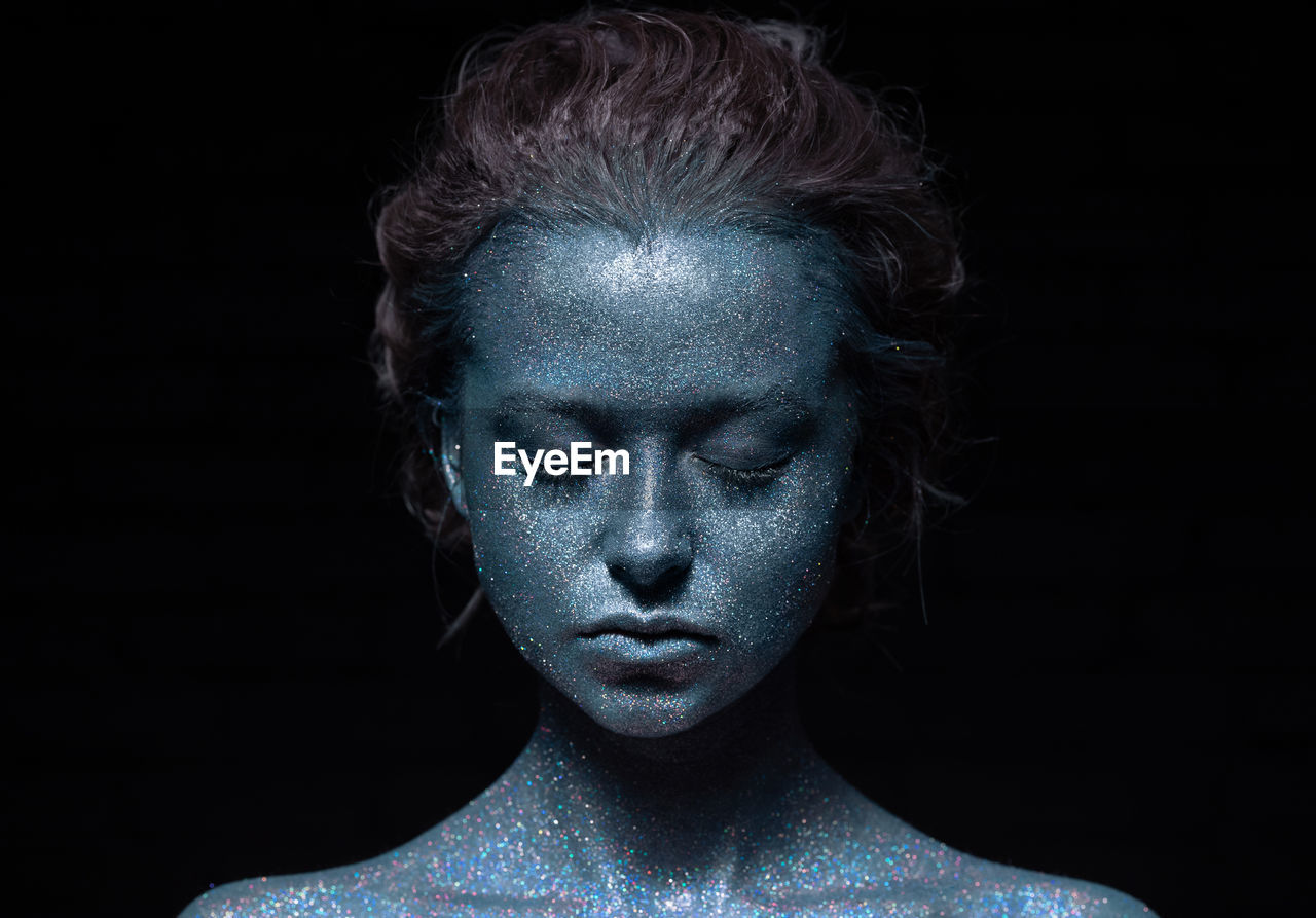 Portrait of a woman with a blue face in glitter