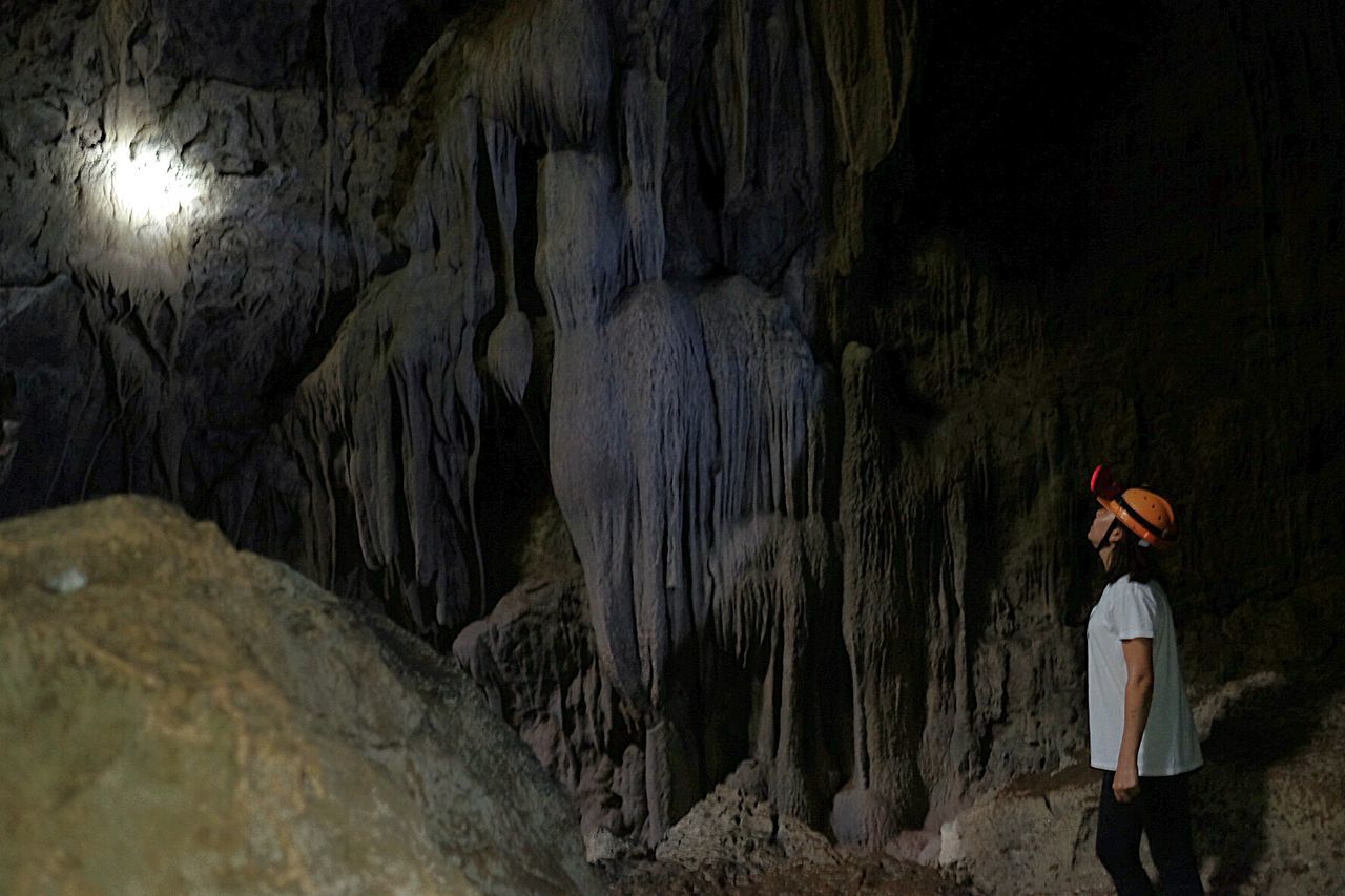 Side view of woman standing in cave
