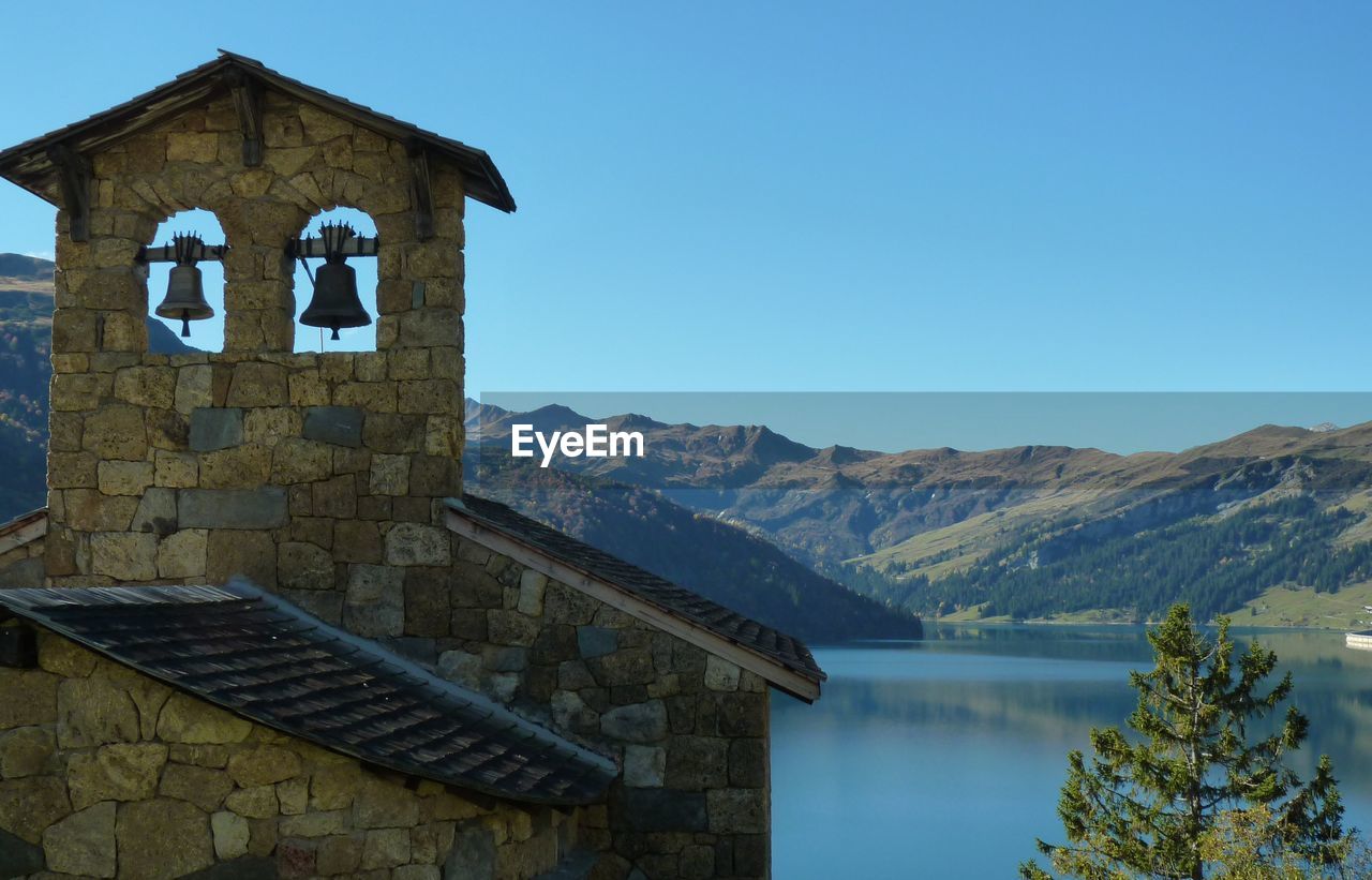 Scenic view of lake and mountains against clear blue sky