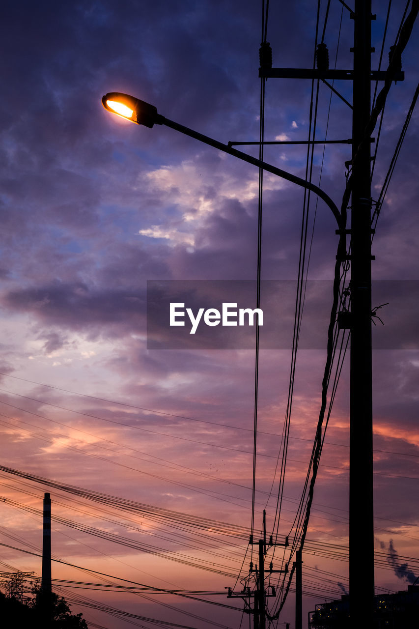 LOW ANGLE VIEW OF ILLUMINATED STREET LIGHTS AGAINST SKY