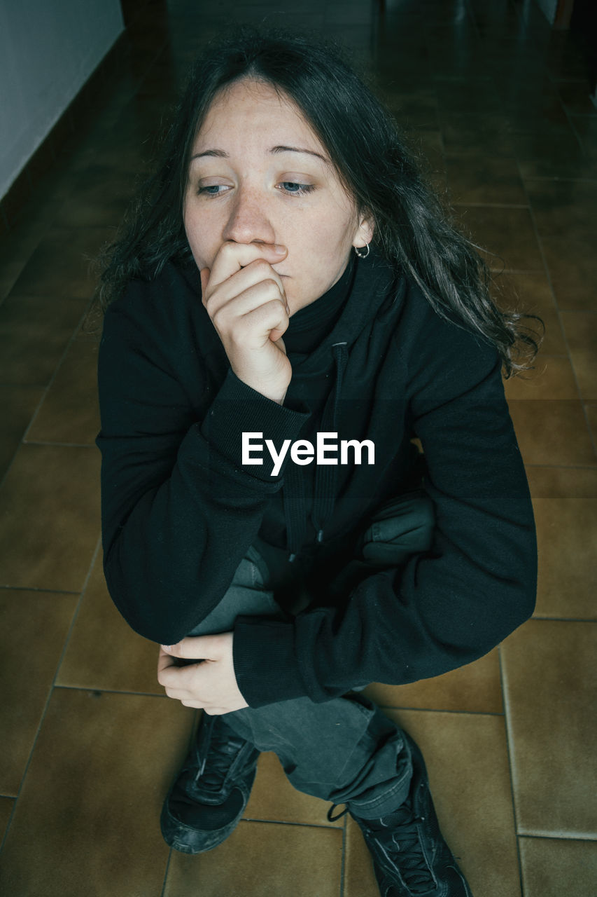 Full length of woman sitting on floor at home