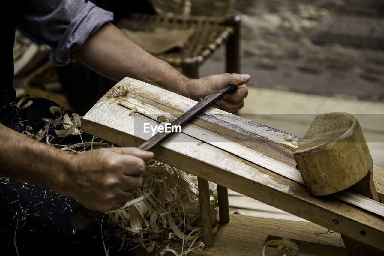 Midsection of carpenter shaving wood in workshop