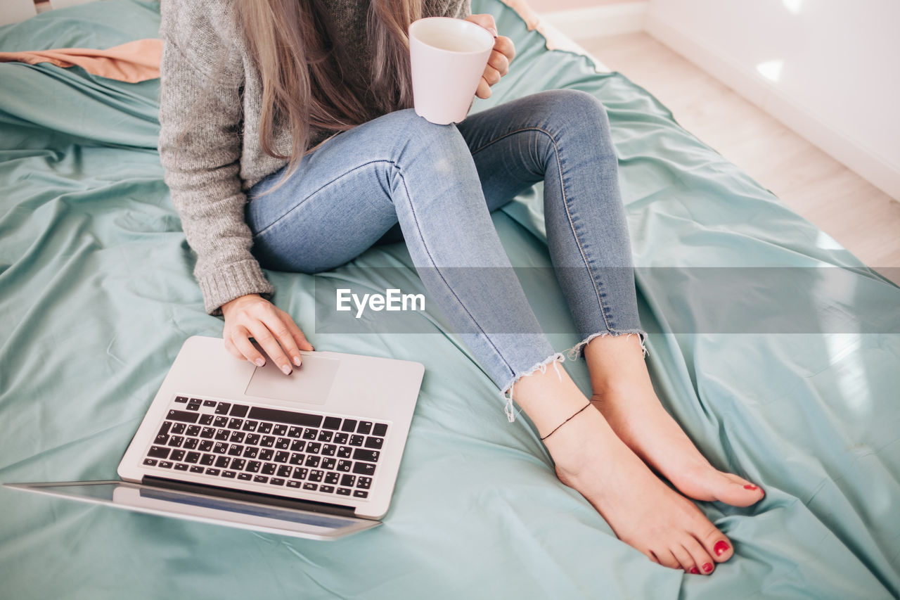 HIGH ANGLE VIEW OF WOMAN USING LAPTOP