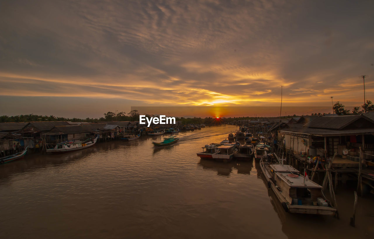 Boats moored at harbor during sunset