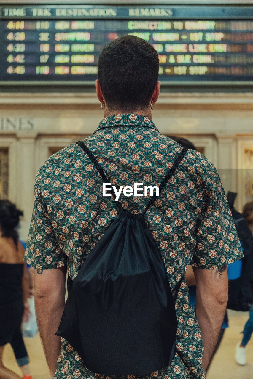 Rear view of man with backpack standing at airport