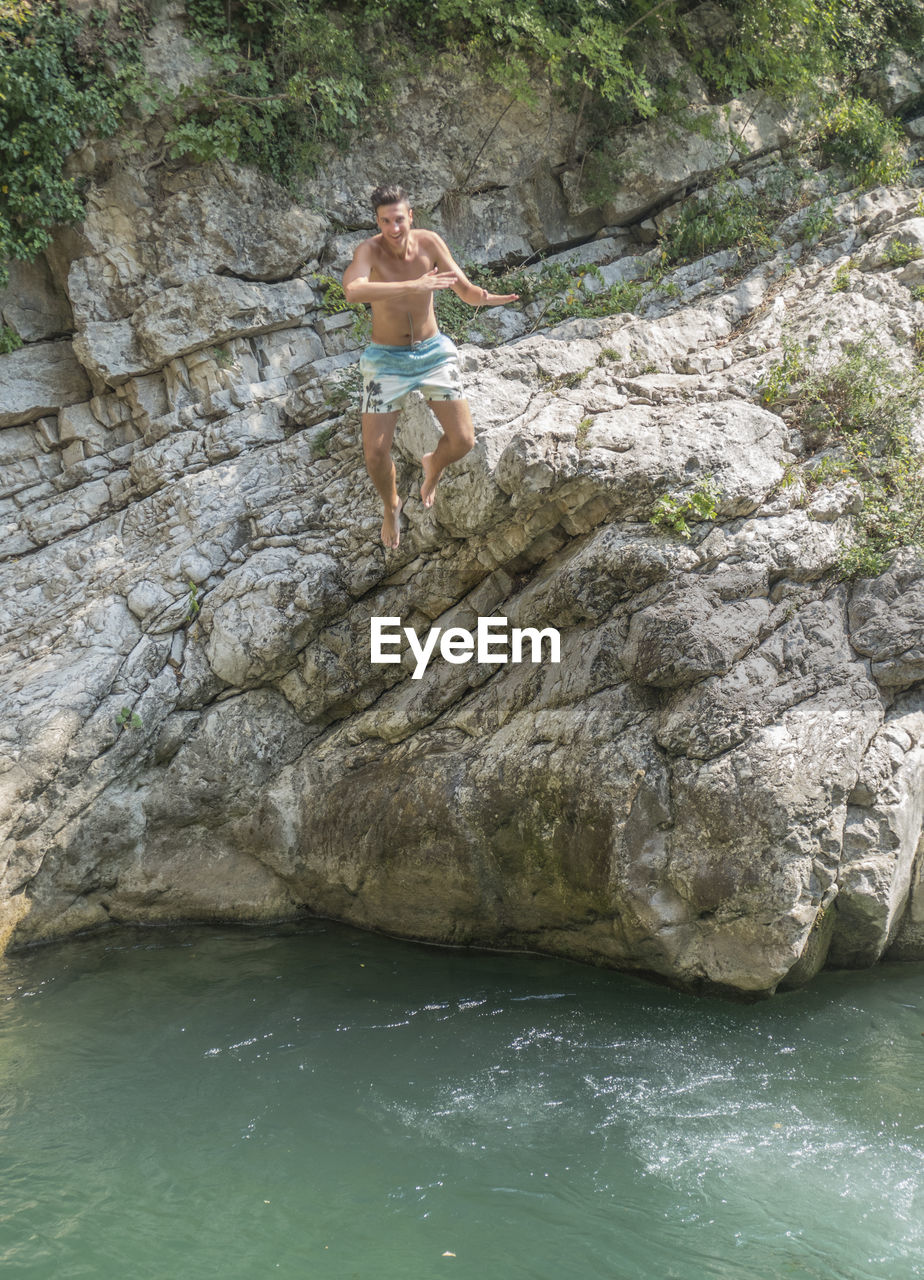 Happy smiling boy dives from a rock