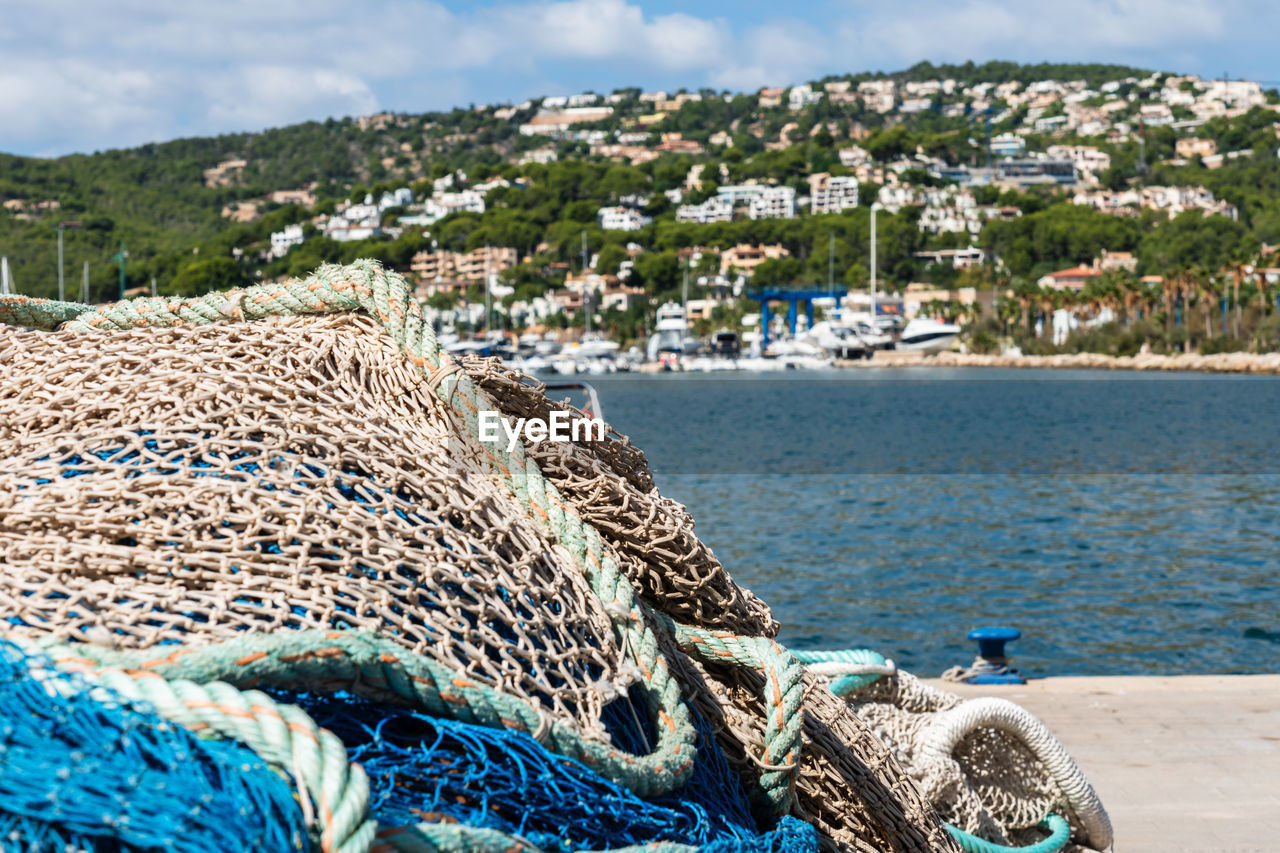 water, fishing industry, fishing, sea, harbor, nature, beach, fishing net, land, coast, nautical vessel, transportation, no people, sky, architecture, day, rope, commercial fishing net, outdoors, vacation, travel destinations, pier, coastline, shore, blue, built structure, buoy, mode of transportation, travel, environment, building exterior, sunlight, mountain, city, cloud, animal, building