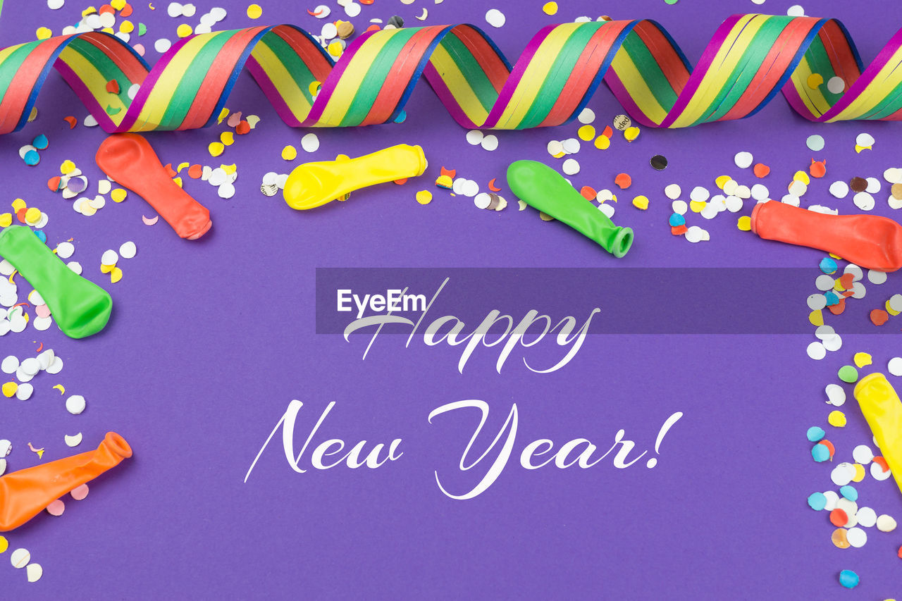 Happy new year text with confetti on purple background