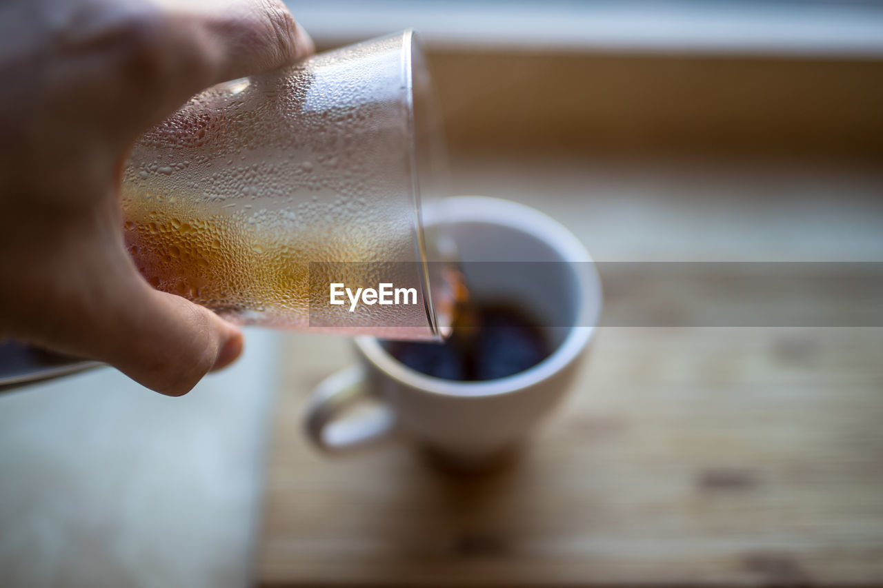 Cropped image of person pouring coffee in cup