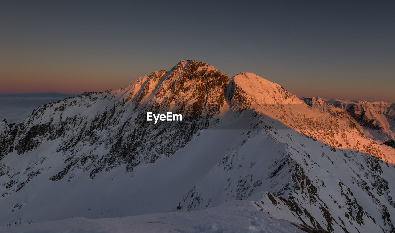 Scenic view of snowcapped mountains against clear sky during winter