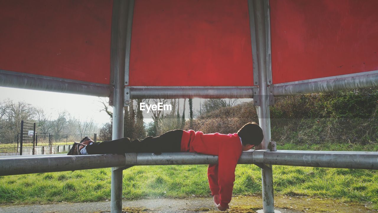 Full length of boy resting on gazebo at park