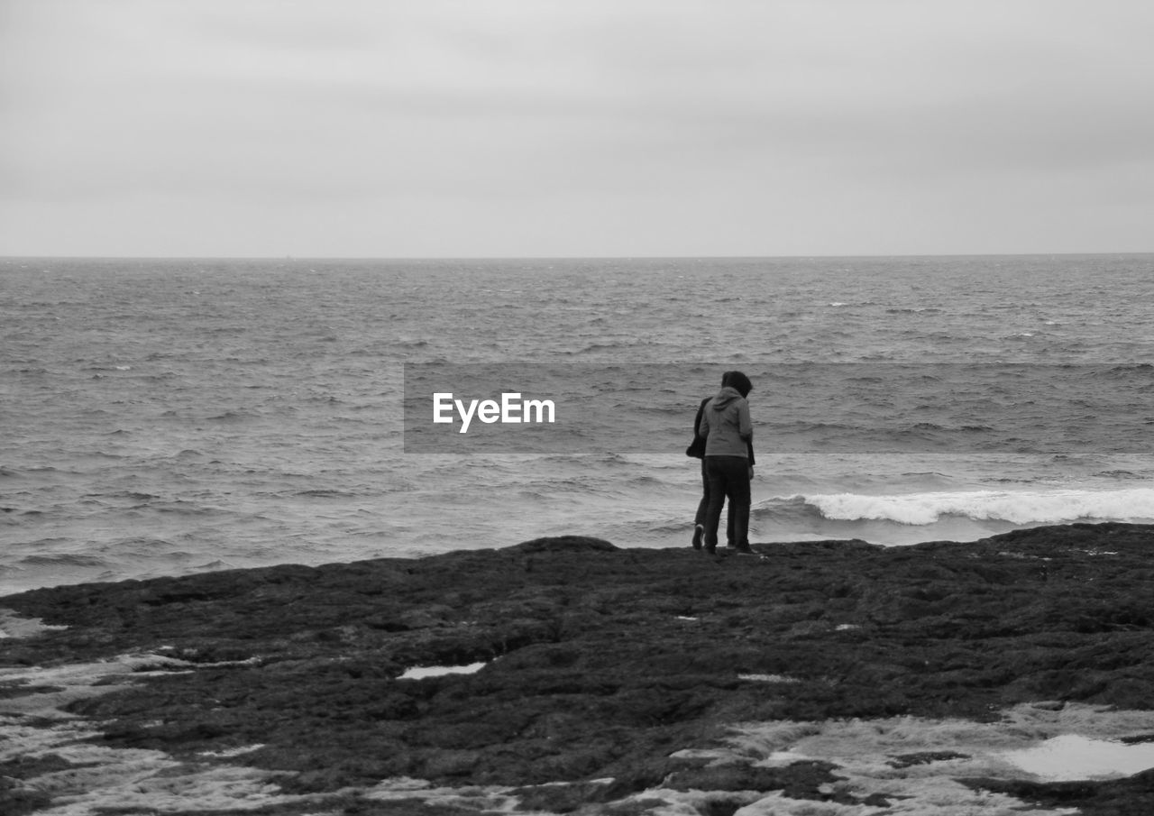 Rear view of two people walking on beach