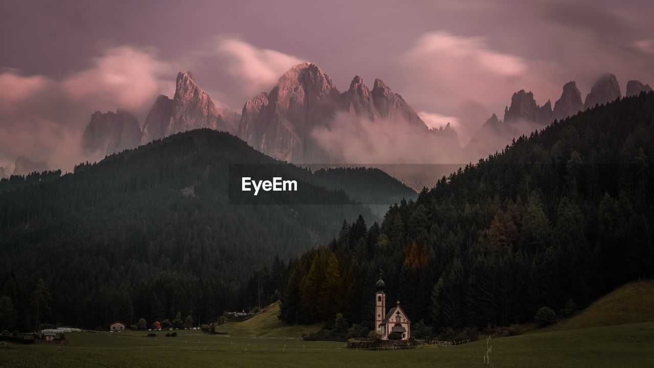 Church on land against mountains at sunset