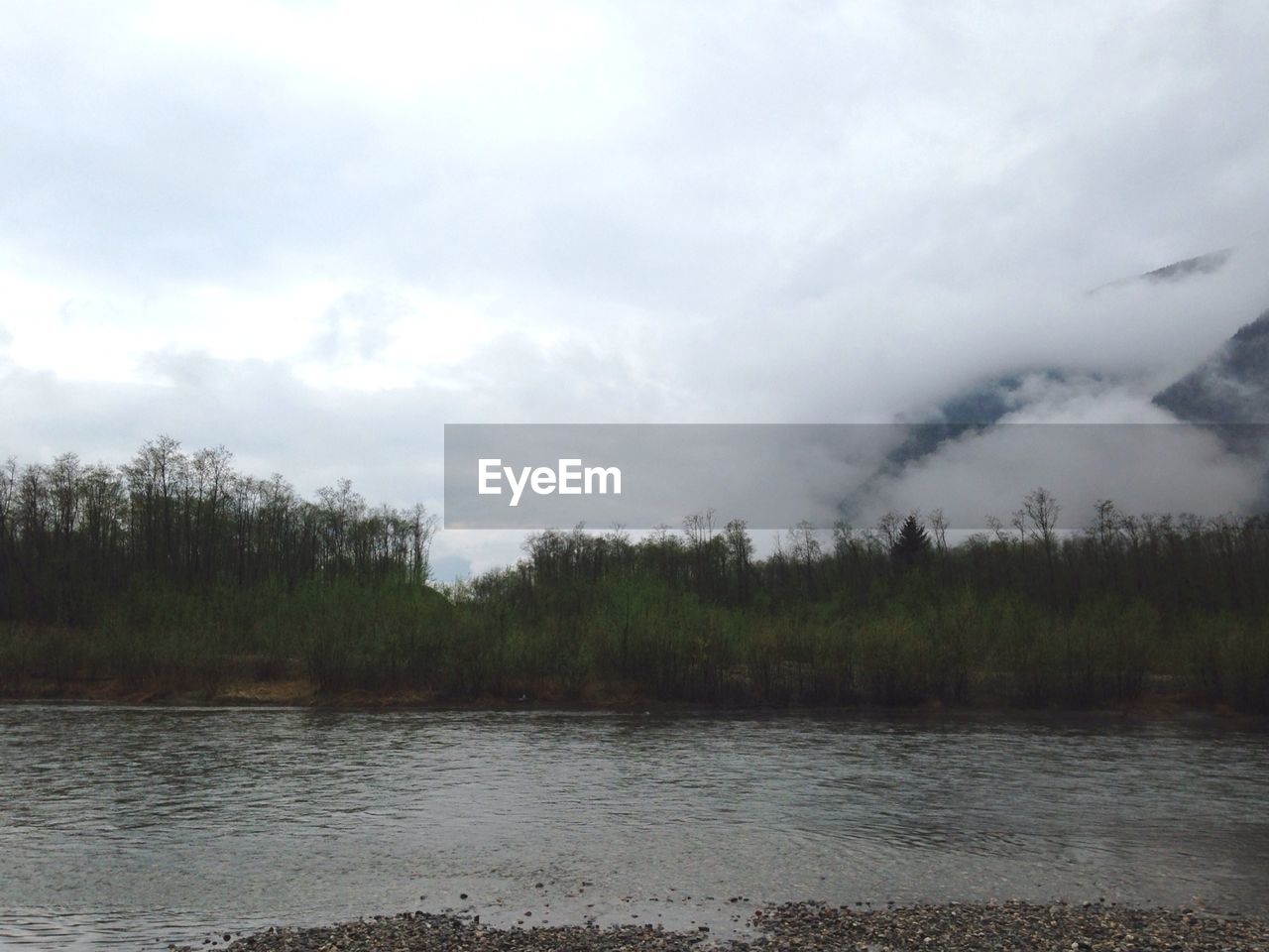 Scenic view of river against cloudy sky