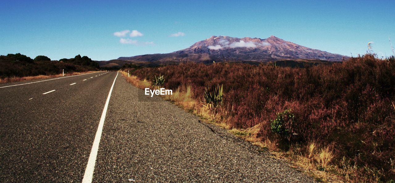 Road amidst landscape against clear blue sky