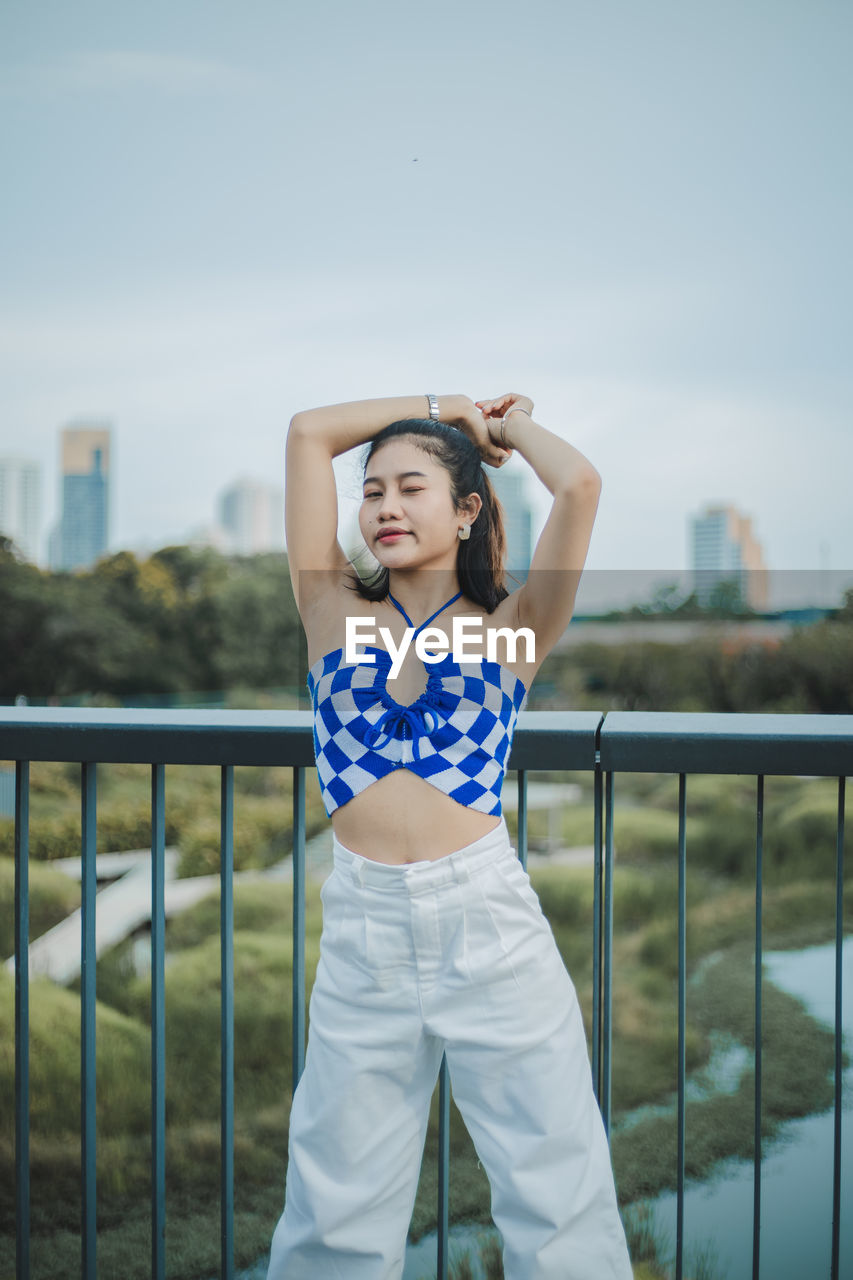 Young woman standing against railing